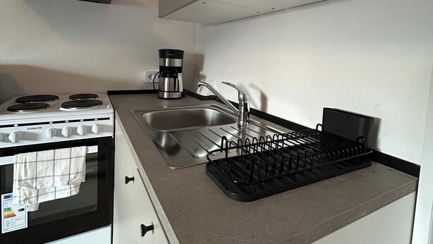 A compact kitchen with a stove, sink, and a coffee maker. - Vrbo Property (Essen)