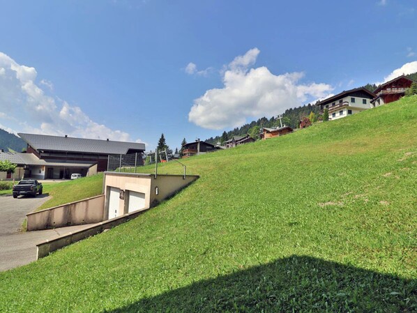 A residential area with houses on a hillside, a parking area, and a clear sky. - Cozy studio with WiFi - 4 guests (Les Gets)