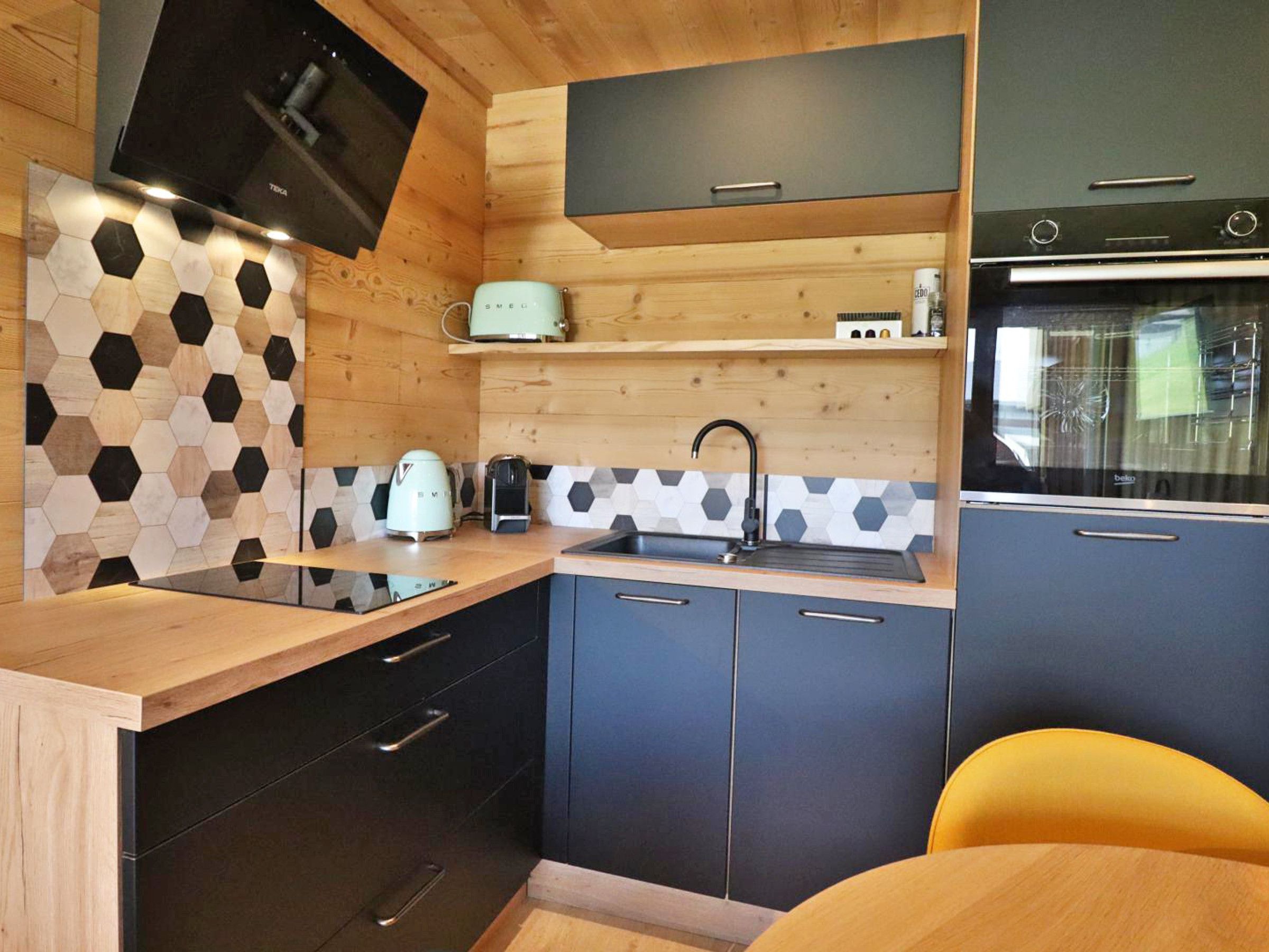 A compact kitchen with a wooden countertop, a built-in oven, and a microwave.