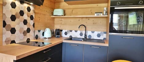 A compact kitchen with a wooden countertop, a built-in oven, and a microwave.