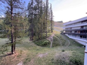 Un edificio con varios balcones que dan a un área boscosa con un sendero de césped.