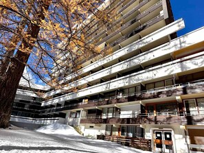 Ein mehrstöckiges Gebäude mit modernem architektonischen Design, das Balkone und einen zentralen Innenhof aufweist.