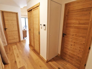A hallway with wooden doors, a light switch, and a window. - Comfortable apartment - 4 guests (Les Gets)