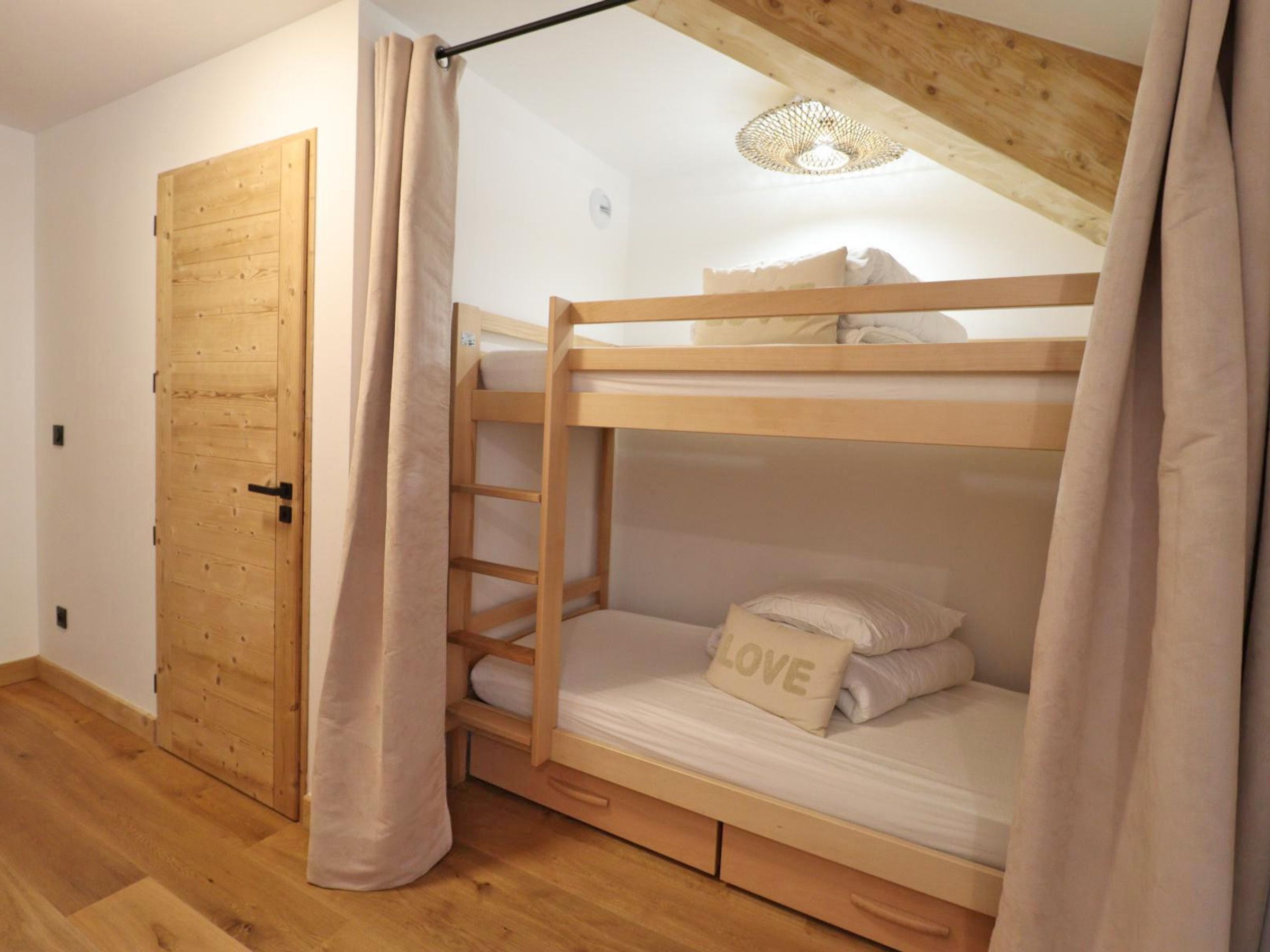Une chambre avec un lit superposé, une porte en bois et un rideau.