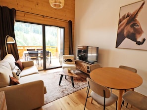 A modern living room with a sofa, TV, and dining area. - Comfortable apartment - 4 guests (Les Gets)