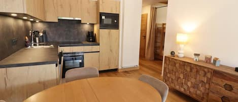 Una cocina moderna con una mesa redonda y sillas, armarios de madera y horno empotrado.