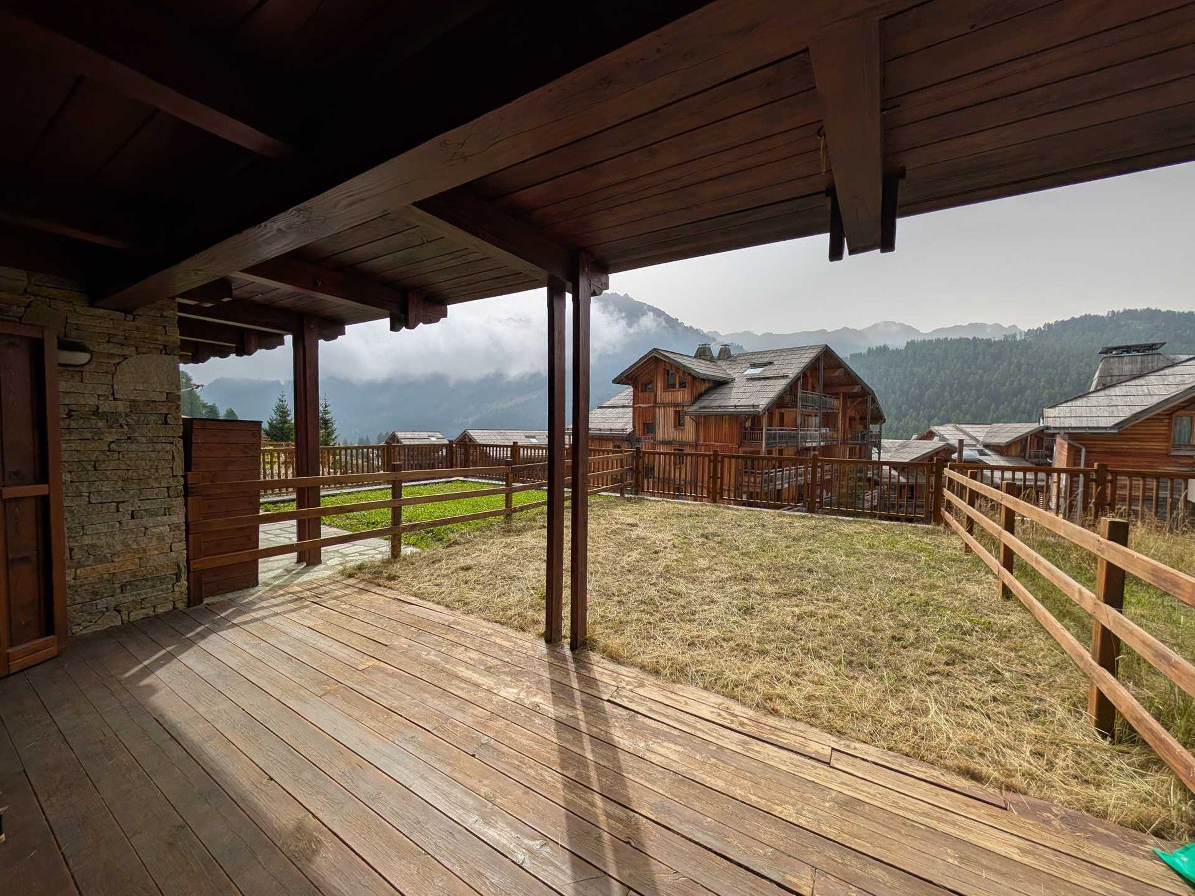 A wooden deck with a view of mountain cabins.