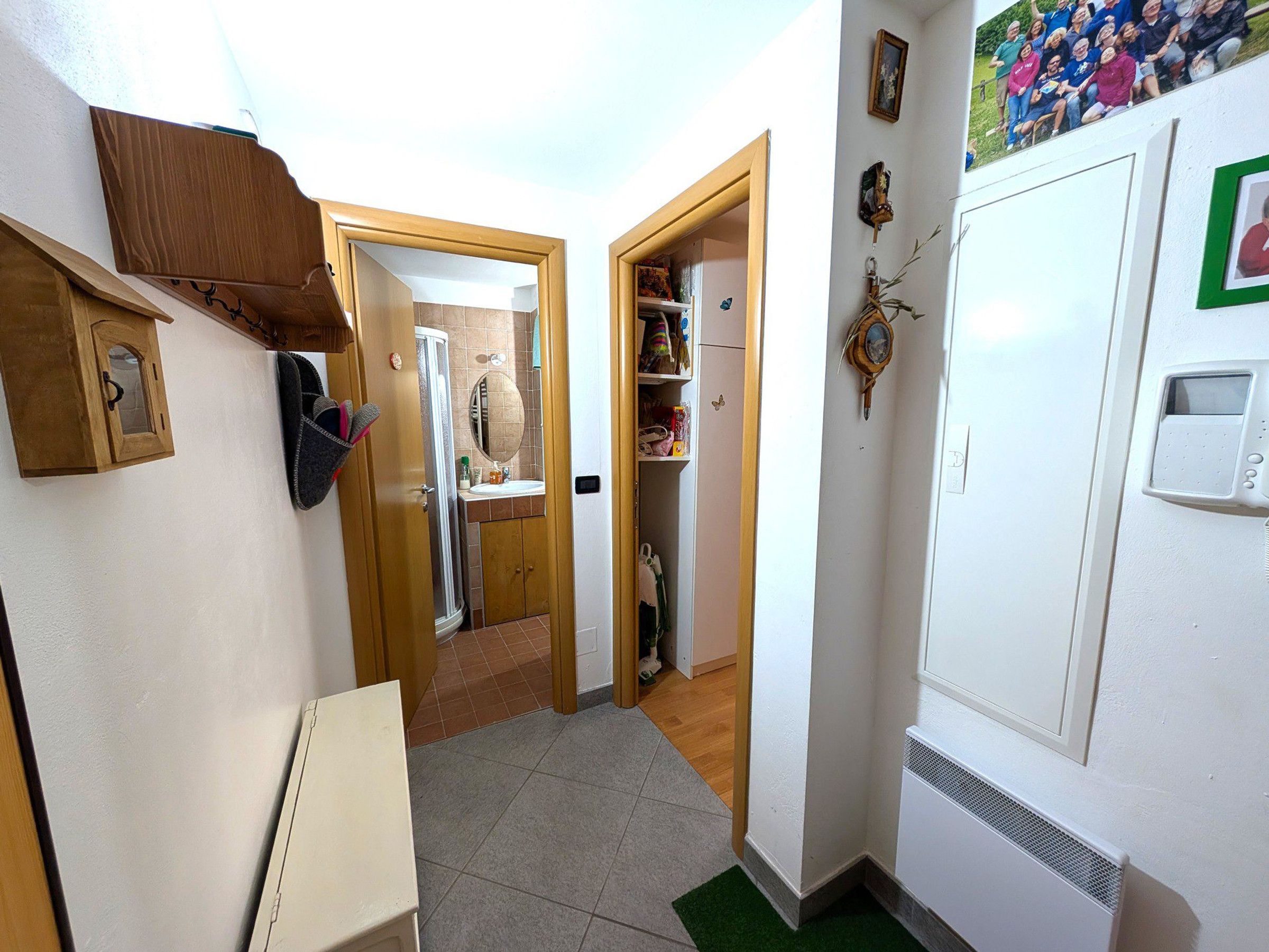 A narrow hallway with a white radiator, a wooden door, and a small white cabinet.