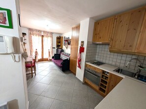 A compact kitchen with wooden cabinets, a tiled backsplash, and a built-in oven.