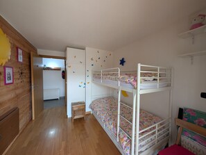 A child's bedroom with bunk beds, wooden flooring, and wall decorations.