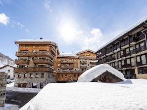 A snow-covered building with multiple balconies and a stone facade.