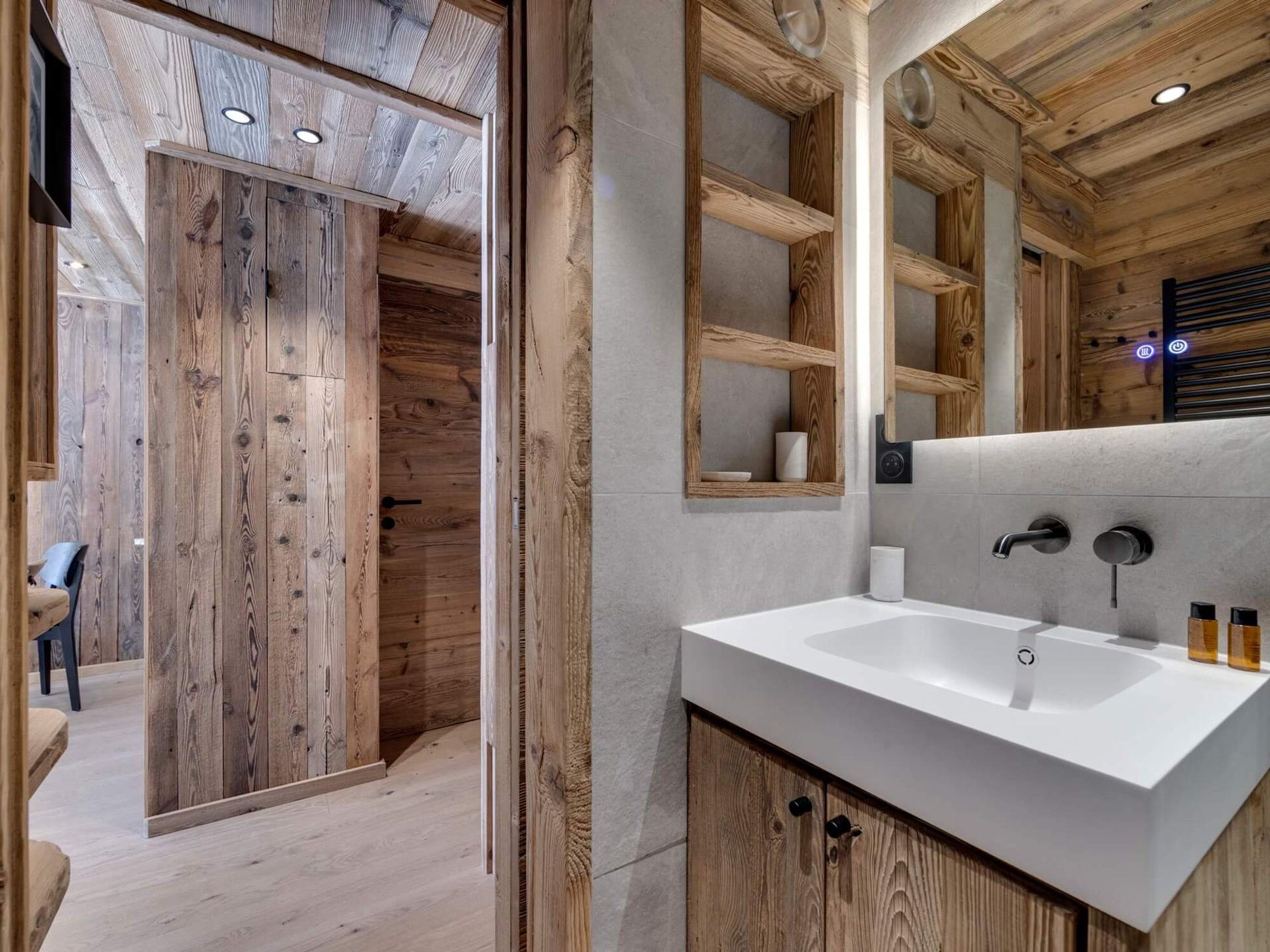 Ein modernes Badezimmer mit einem Holzbadschrank, einem großen Spiegel und einem weißen Waschbecken.