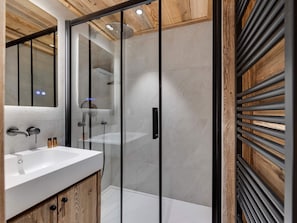 A modern bathroom with a glass-enclosed shower, a wooden vanity, and a large mirror.
