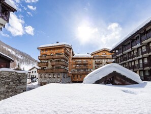 A snow-covered building with multiple balconies and a stone facade. - Renovated apartment at the foot of the slopes - 2 guests (Val-d'Isère)