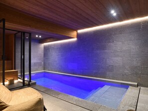 Un espace spa doté d’une piscine, d’un plafond en bois et de murs en pierre.