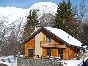 A wooden cabin with a balcony, set against a snowy mountain backdrop. - Spacious chalet mountain view - 10 guests (Les Deux Alpes)