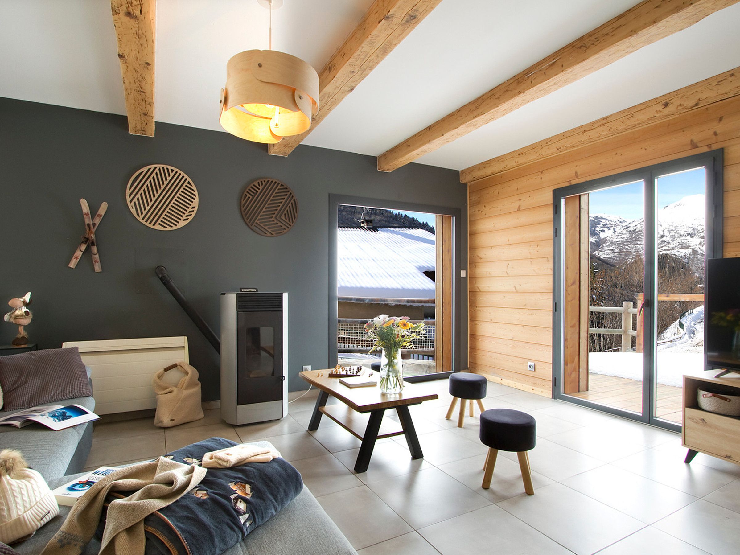 A modern living room with a fireplace, a sofa, a dining table with chairs, and a large window offering a mountain view.