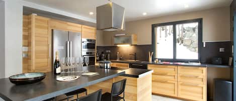 Una cocina moderna con una isla central, armarios de madera y electrodomésticos de acero inoxidable, además de un amplio ventanal.