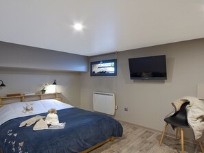 A hotel room with a bed, a chair, a TV, a window, and a lamp. - Spacious chalet mountain view - 10 guests (Les Deux Alpes)