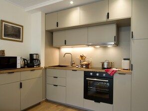 A compact kitchen with a microwave, coffee maker, sink, and oven. - Charming apartment at foot of slopes - 6 guests (Les Deux Alpes)
