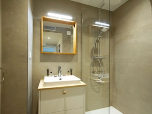 A modern bathroom with a glass shower enclosure, a sink with a mirror above it, and a wooden vanity. - Charming apartment at foot of slopes - 6 guests (Les Deux Alpes)