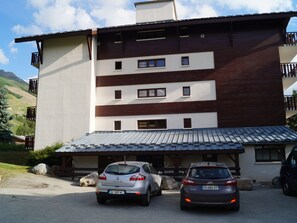 A multi-story building with a parking area in front. - Central T1 loft with parking - 4 guests (Les Deux Alpes)