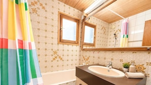 Ein Badezimmer mit Badewanne, Waschbecken, Spiegel und Duschvorhang.