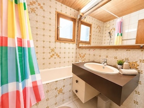 A bathroom with a bathtub, a sink, a mirror, and a shower curtain. - Central T1 loft with parking - 4 guests (Les Deux Alpes)