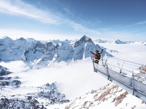 A person standing on a glass bridge with snow-covered mountains in the background. - Ideal ski-in/ski-out apartment - 6 guests (Les 2 Alpes 1650)