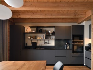 Eine moderne Küche mit dunklen Schränken, einer Holzbalkendecke und einem eingebauten Ofen.