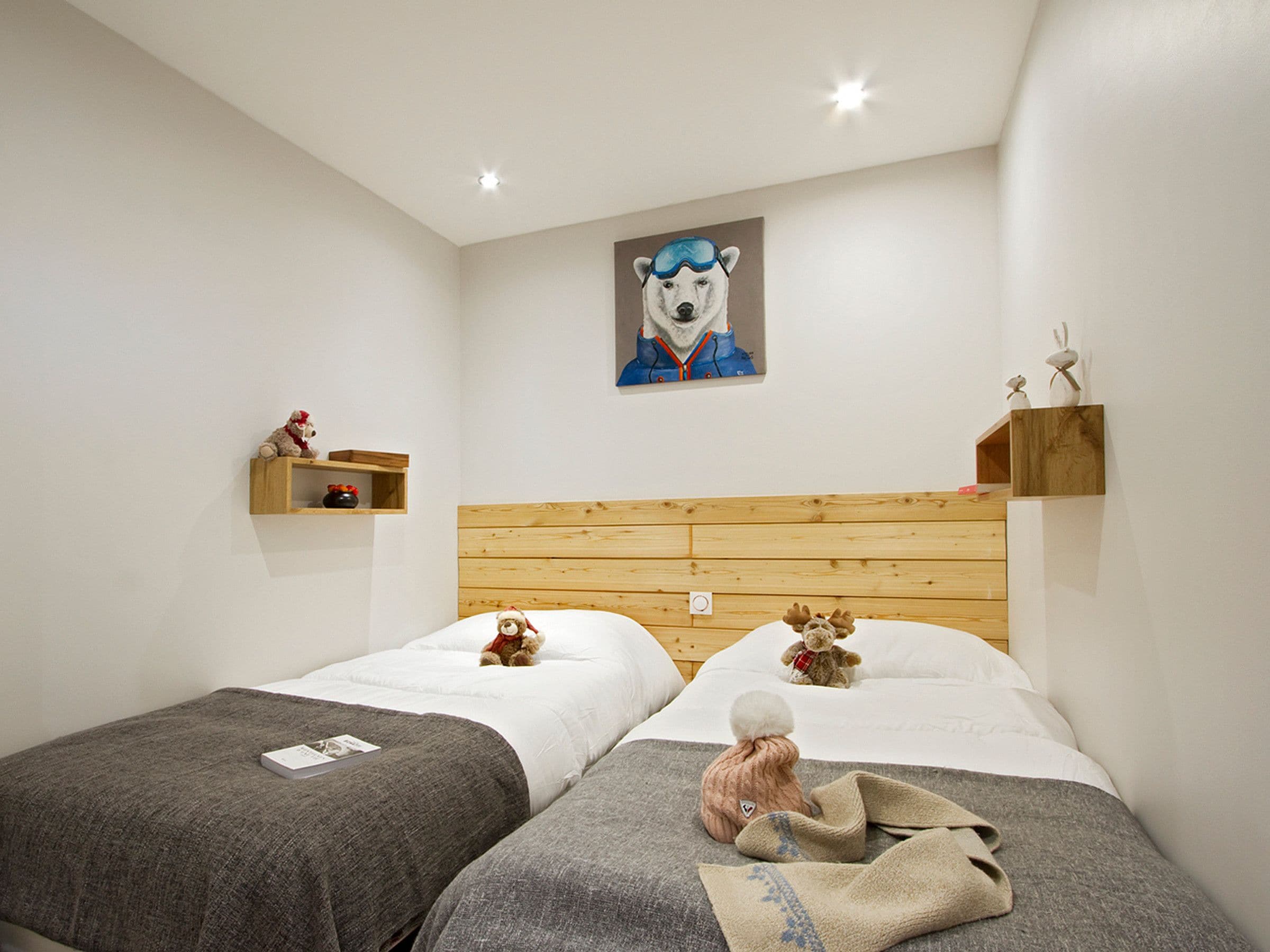 Hotelkamer met twee bedden, een houten hoofdbord, een schilderij van een ijsbeer en een klein plankje met decoratieve objecten.