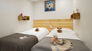 Ein Hotelzimmer mit zwei Betten, einem hölzernen Kopfteil, einem Bild eines Eisbären und einem kleinen Regal mit Dekoration.