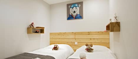 Habitación de hotel con dos camas, cabecero de madera, un cuadro de un oso polar y un pequeño estante con objetos decorativos.