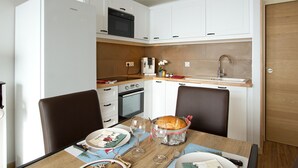 Eine kleine Küche mit weißen Schränken, einer Mikrowelle, einem Backofen und einem Spülbecken.