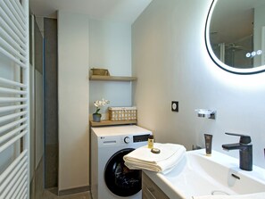 A modern bathroom with a built-in washing machine, a sink with a black faucet, and a mirror above the sink. - Apartment with view of La Muzelle - 4 guests (Les Deux Alpes)