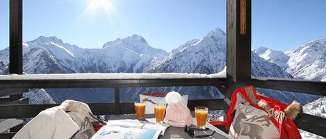 Un tavolo con un menù, un bicchiere di succo d'arancia e una bottiglia di succo, sullo sfondo di una montagna innevata.