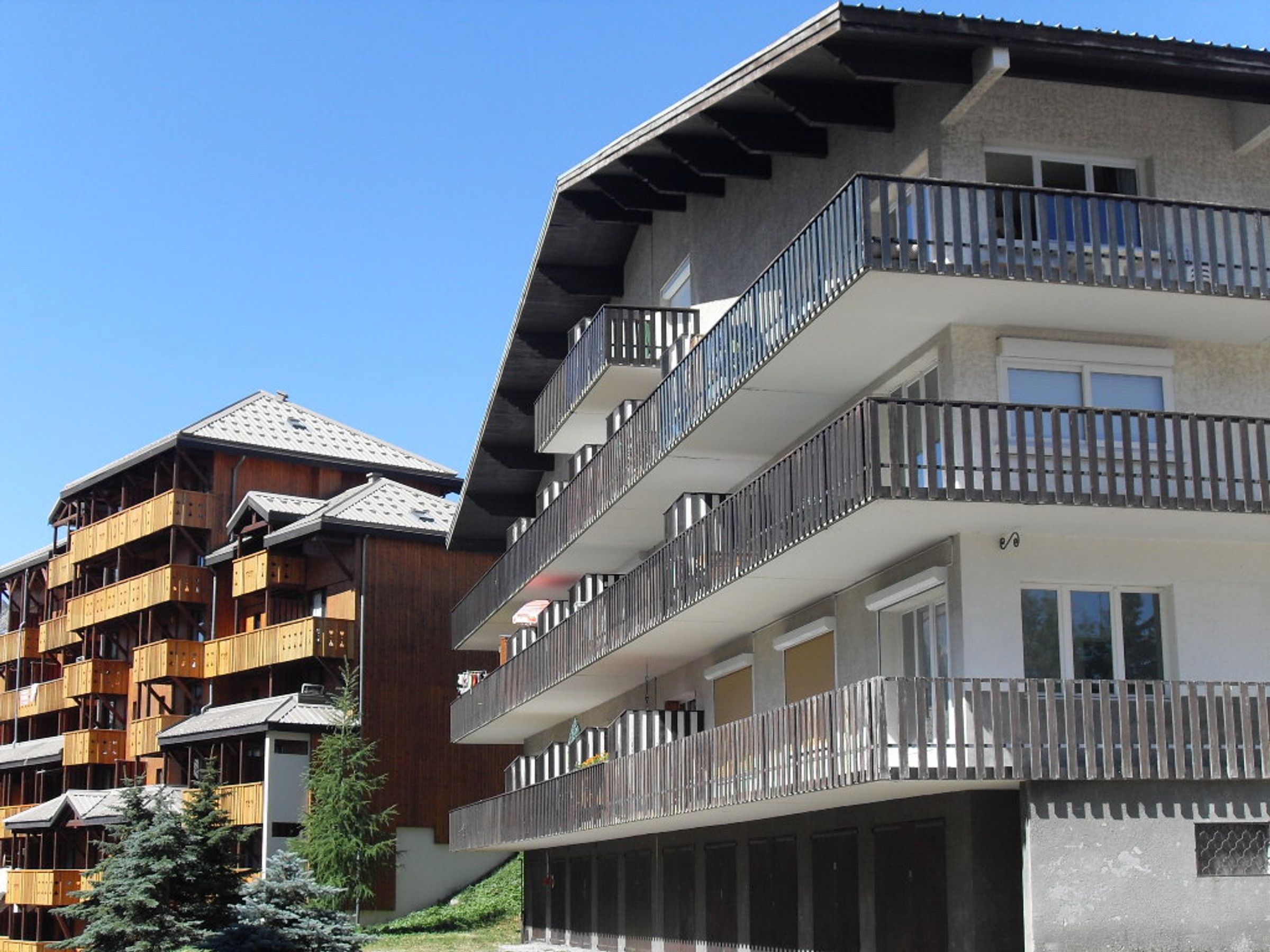 A multi-story hotel with balconies, a wooden facade, and a clear sky.