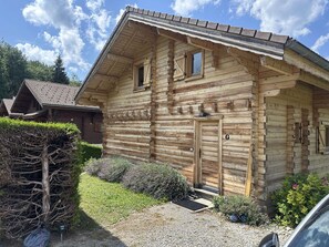 A wooden log cabin with a sloped roof, a front door, and two windows.