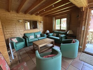 Ein Holzblockbau-Innenraum mit einer Sofaecke, einem Couchtisch und einem kleinen runden Tisch.