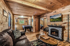 A cozy cabin interior with a billiards table, leather sofa, fireplace, and a television mounted on the wall. - Your Home Away From Home 3 bedrooms, 2 bathrooms, 7 minutes to Pigeon Forge (Sevierville)