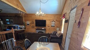 Un intérieur en bois comprenant une table à manger, des chaises, un téléviseur et un coin cuisine.