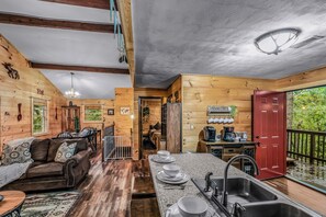 A cozy cabin interior with a living area, kitchen, and a red door leading to a balcony. - Your Home Away From Home 3 bedrooms, 2 bathrooms, 7 minutes to Pigeon Forge (Sevierville)