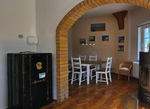 Ein Essbereich mit einer Ziegelbogenarchitektur, weißen Stühlen, einem Holztisch und einem Kamin.
