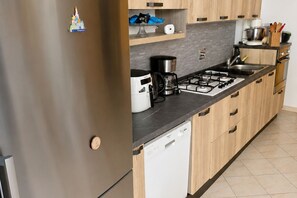 A modern kitchen with a built-in dishwasher, a gas stove, and a coffee maker. - Charming Holiday Home in Sanremo Near La Pigna (Sanremo)