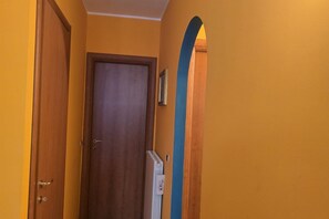 A hallway with a wooden door, a radiator, and a blue archway. - Charming Holiday Home in Sanremo Near La Pigna (Sanremo)