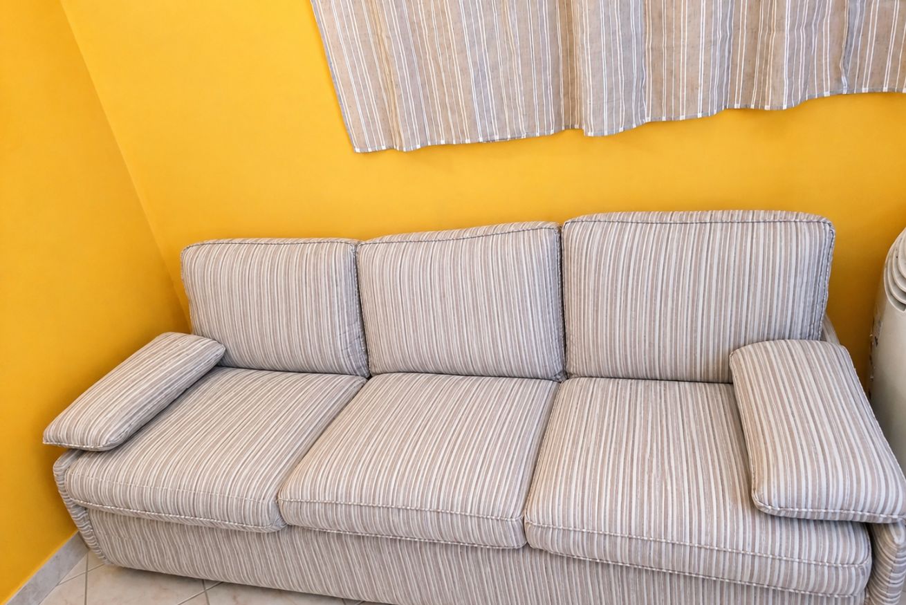 Un sofá a rayas con un cojín a juego frente a una pared amarilla.