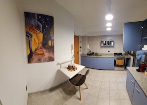 Eine kompakte Küche mit Essbereich, einem Bild an der Wand und einem kleinen Tisch mit Stühlen.