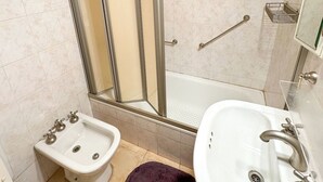 A bathroom with a shower enclosure, bidet, sink, and a mirror. - Three bedrooms with parking and security. (Buenos Aires)