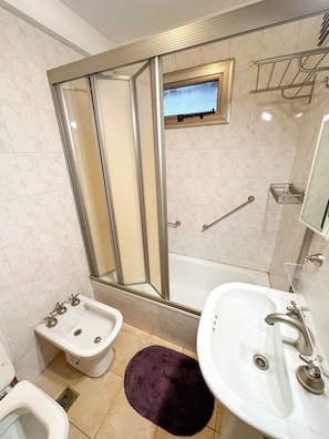 A bathroom with a shower enclosure, bidet, sink, and a mirror. - Three bedrooms with parking and security. (Buenos Aires)