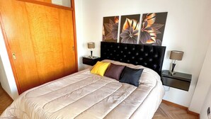 A bedroom with a bed, a wooden wardrobe, a nightstand, a wall-mounted lamp, and a painting. - Three bedrooms with parking and security. (Buenos Aires)